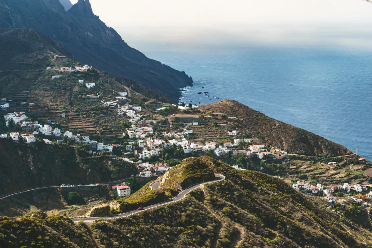 Küstendorf an grünem Berghang mit Blick aufs Meer