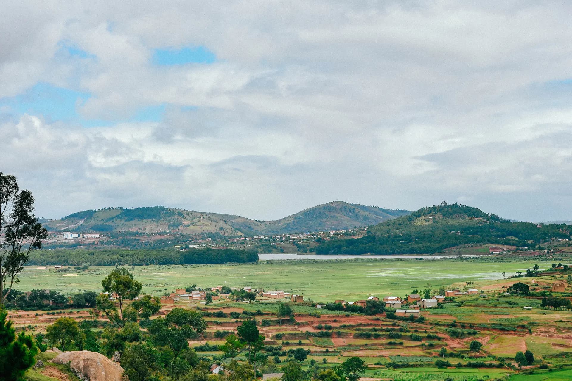 a scenic view of a valley with a lake in the distance