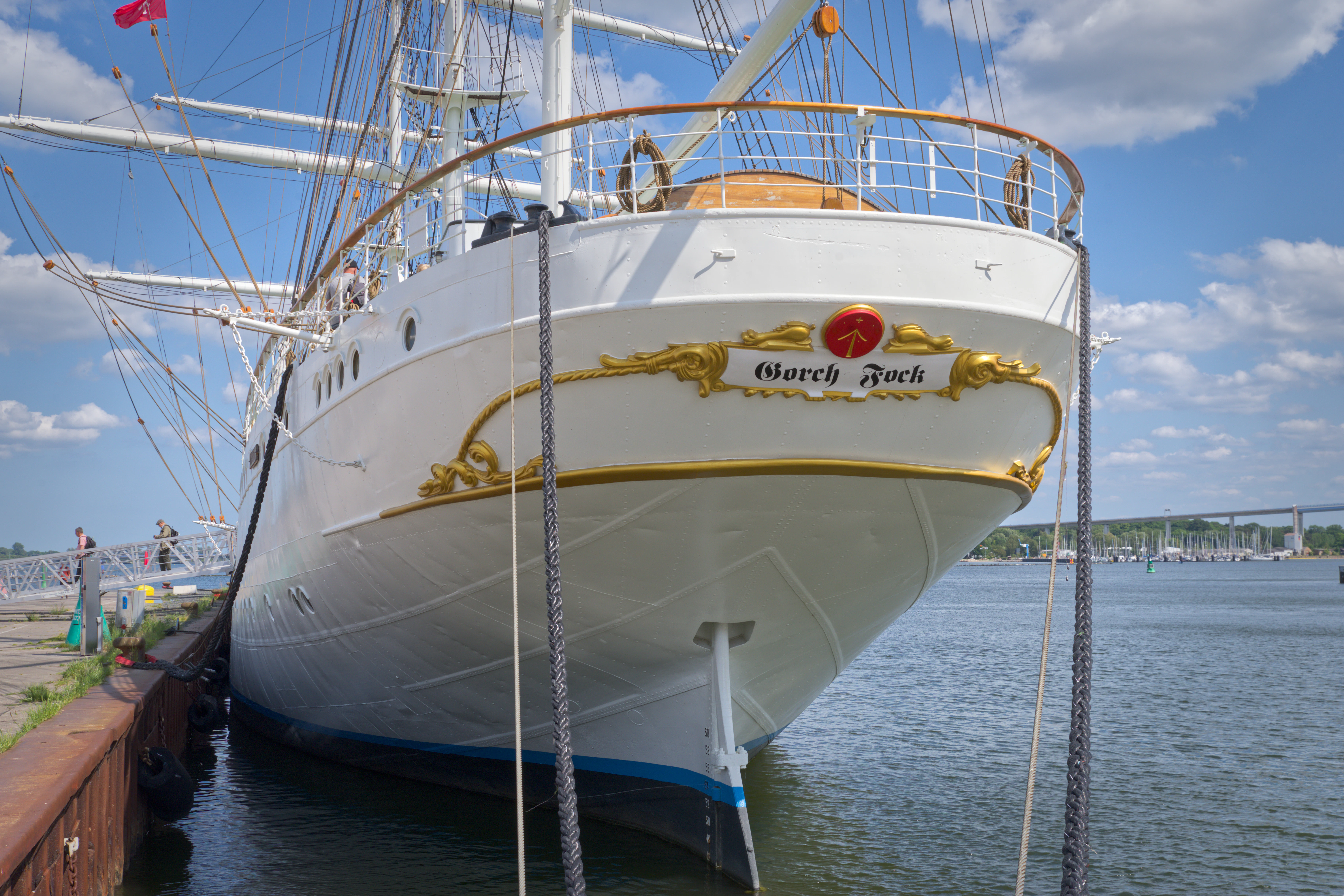 A large white sailing ship docked at a pier.