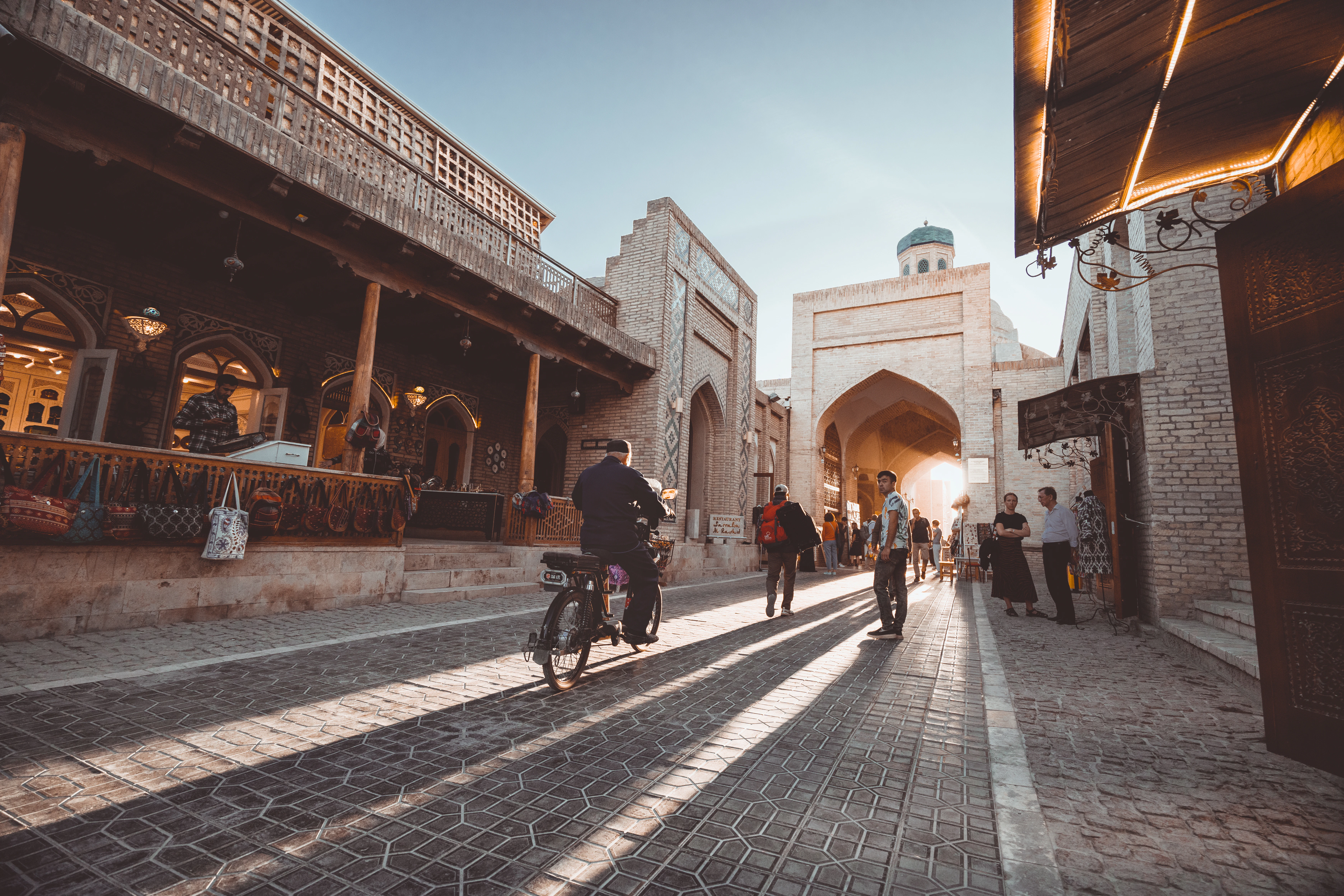 a person riding a bicycle on a brick road between buildings