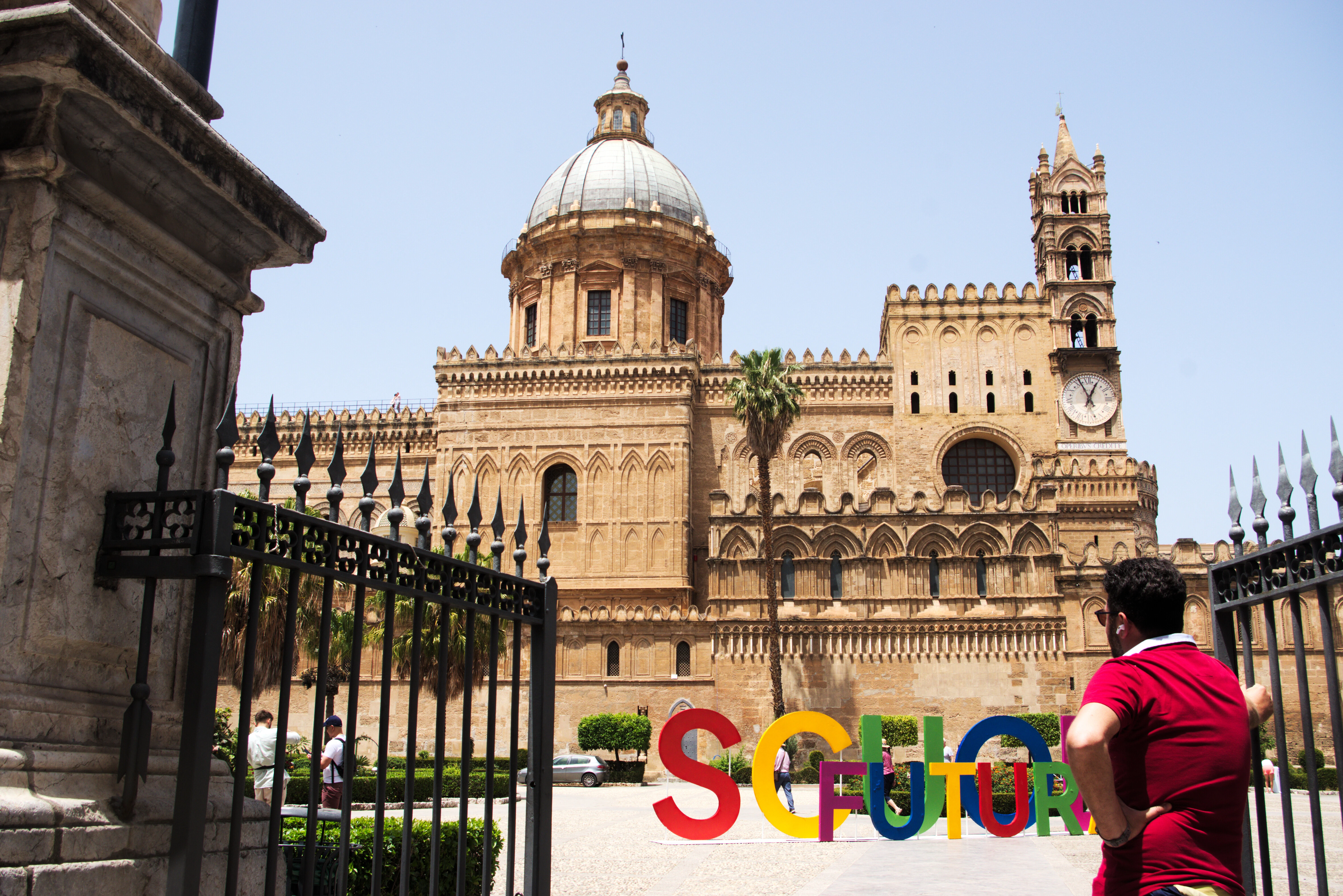 a man in a red shirt standing in front of a building