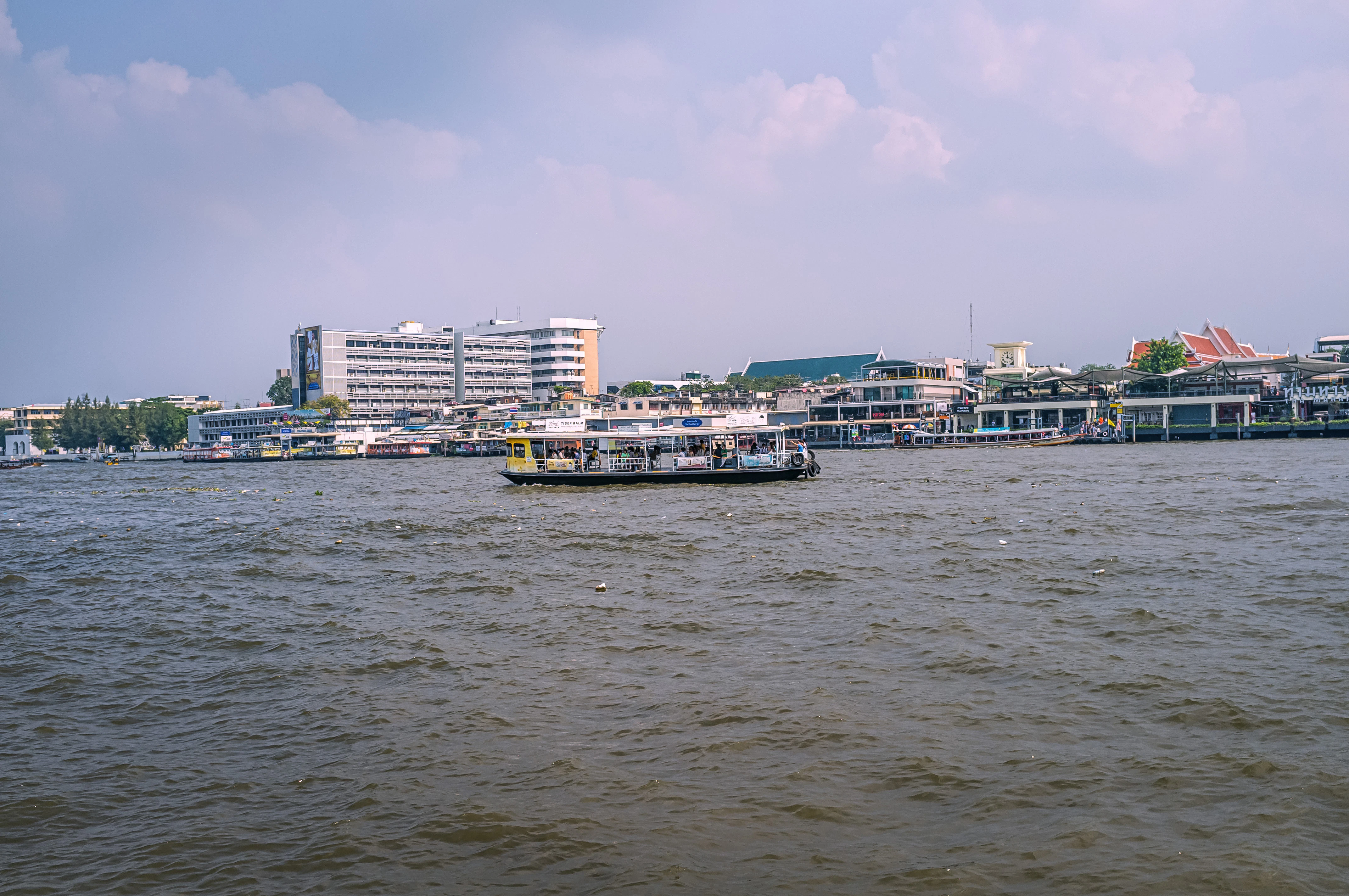 white and blue boat on sea near city buildings under blue sky during daytime