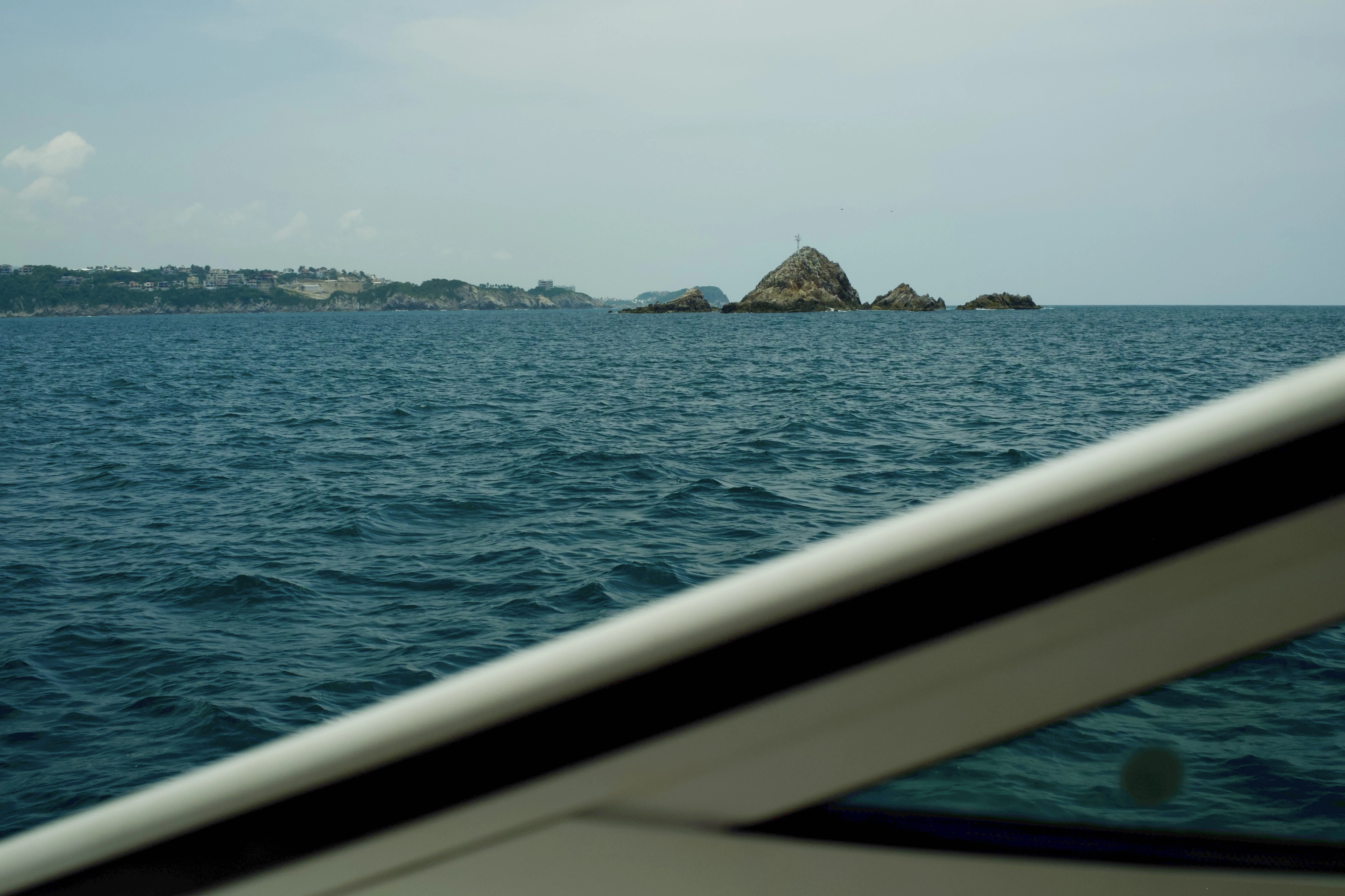 Boat sailing towards rocky islands and distant coastline.