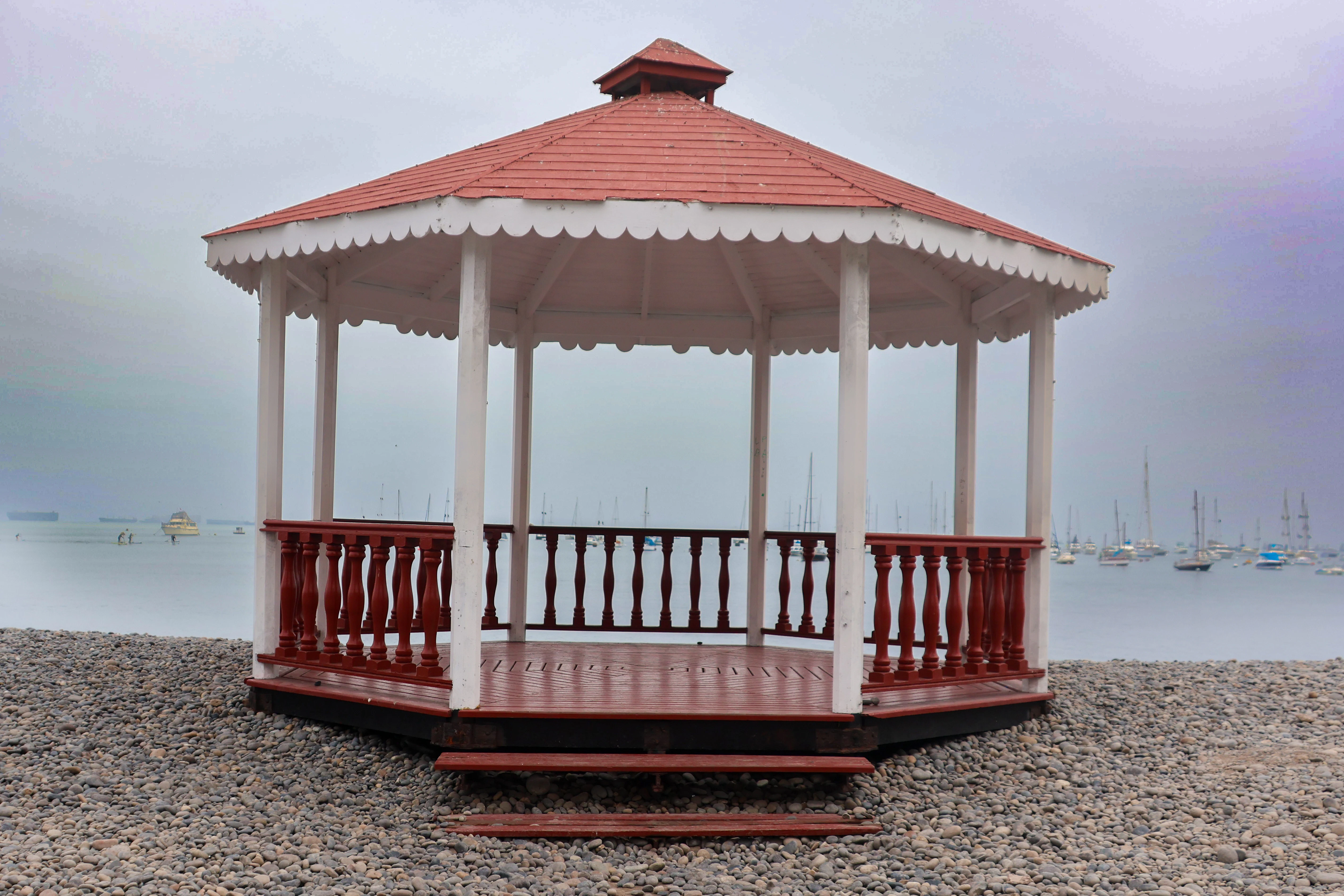A red and white gazebo sitting on top of a sandy beach