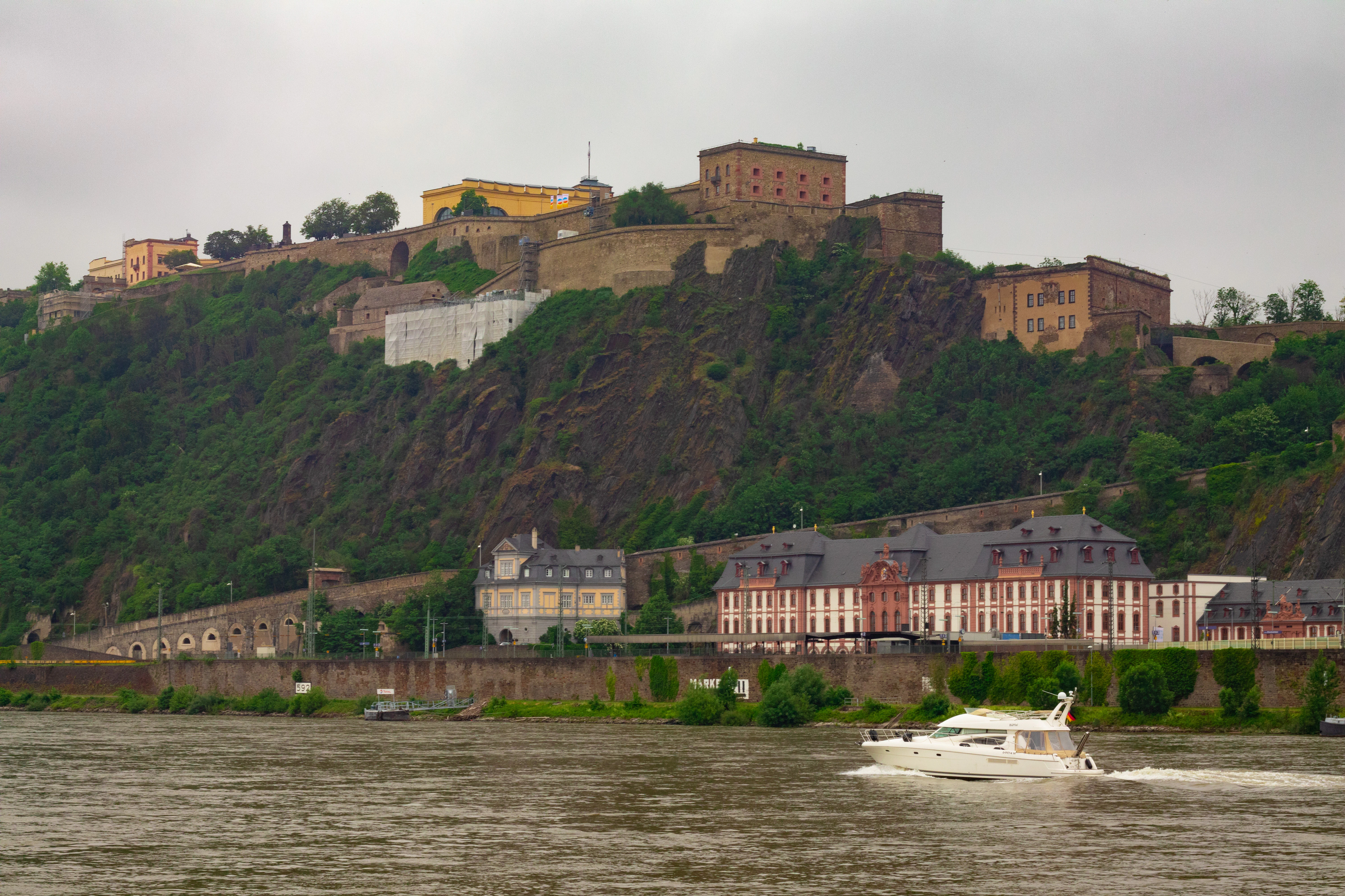 a boat traveling down a river next to a lush green hillside
