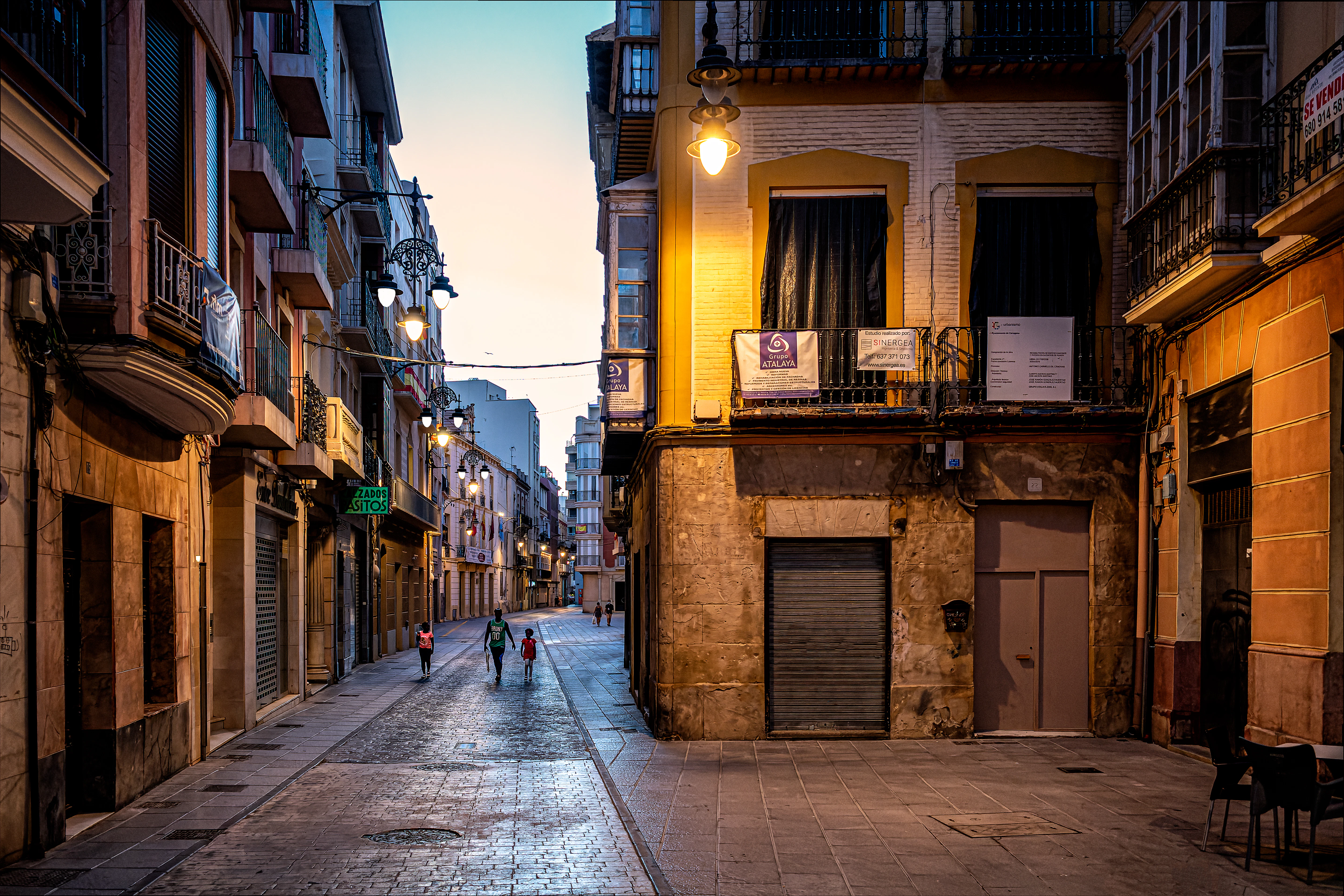a narrow city street with people walking down it