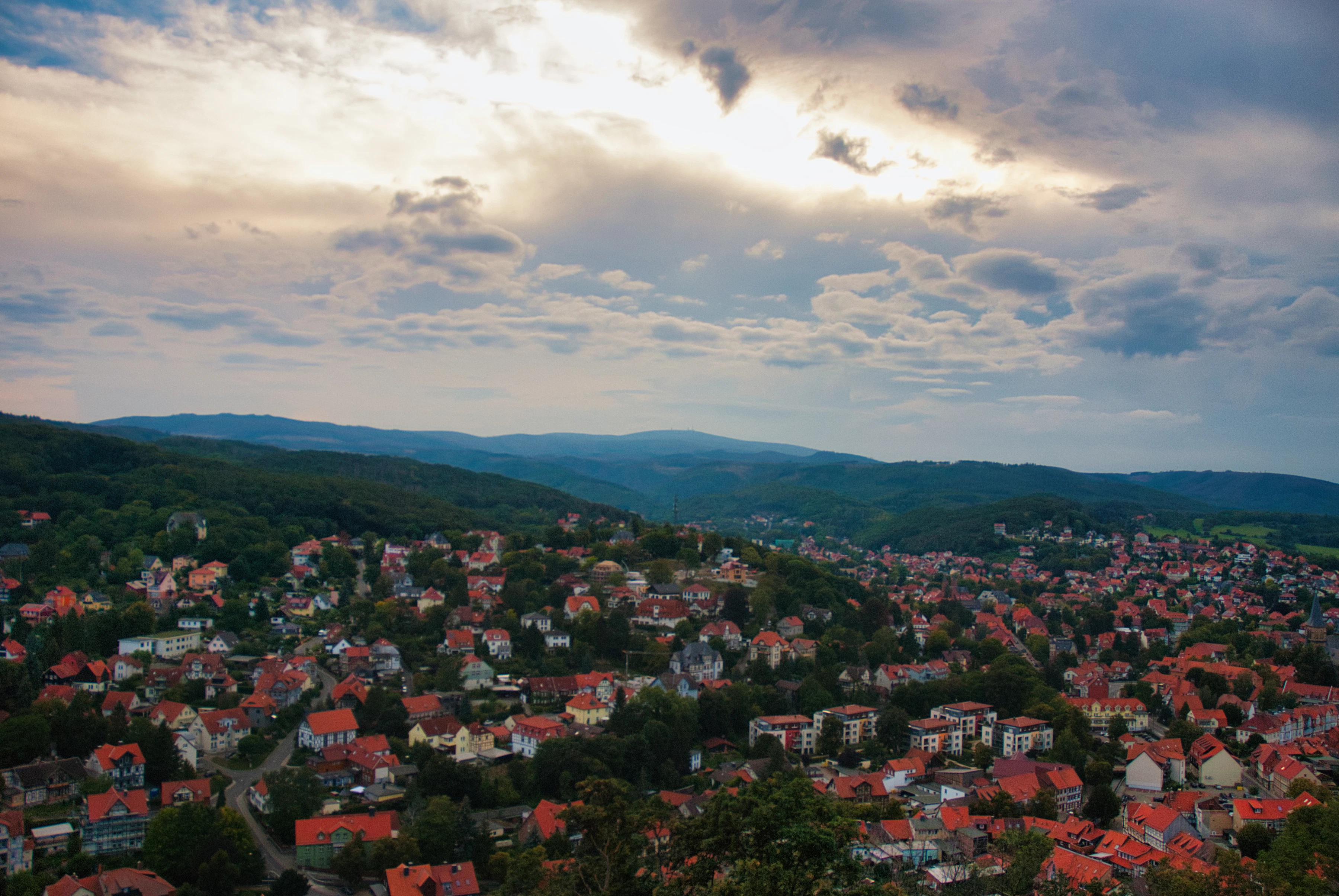 Hilly town with red roofs under cloudy sky