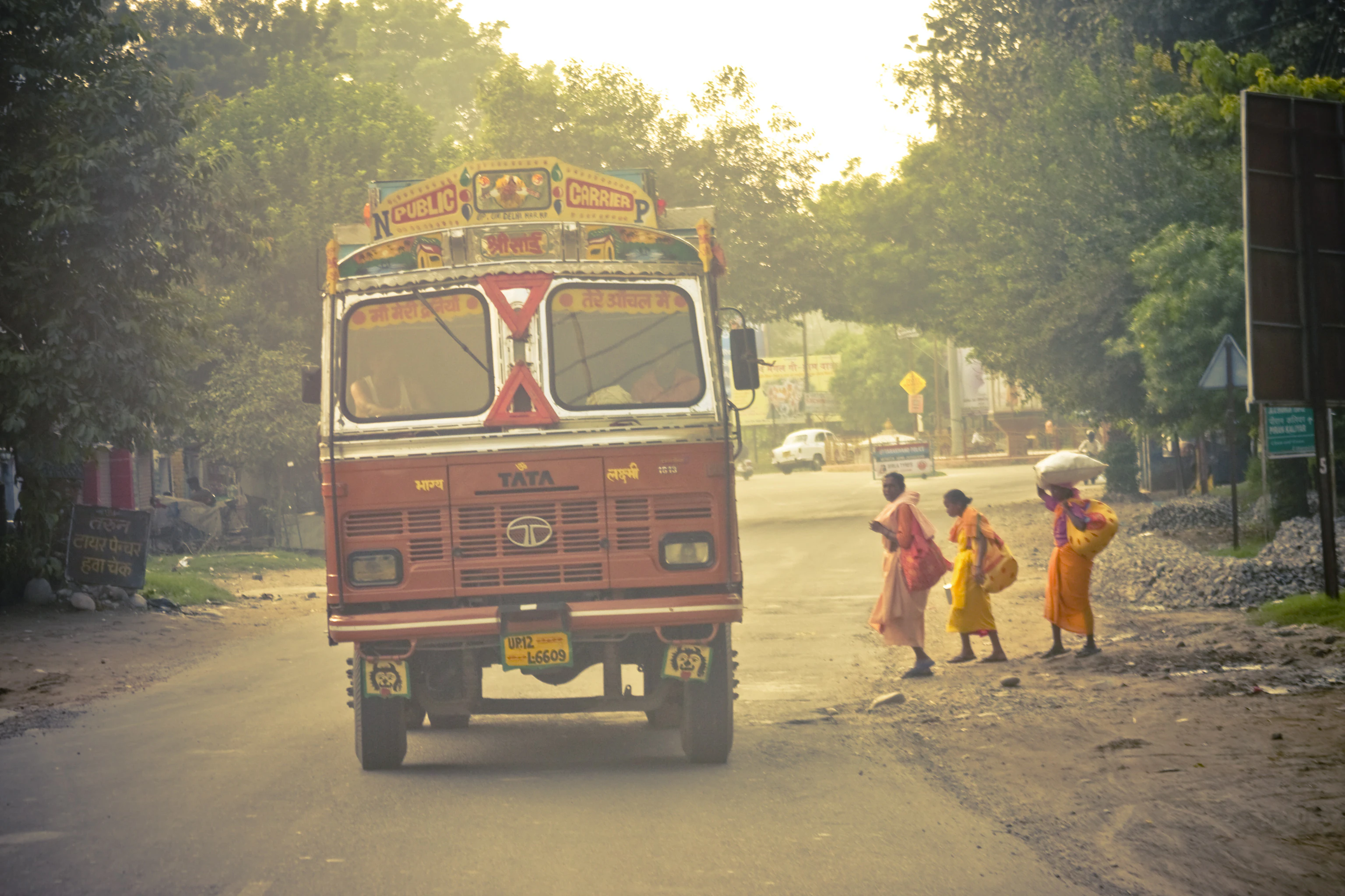 a red bus driving down a street next to a group of people