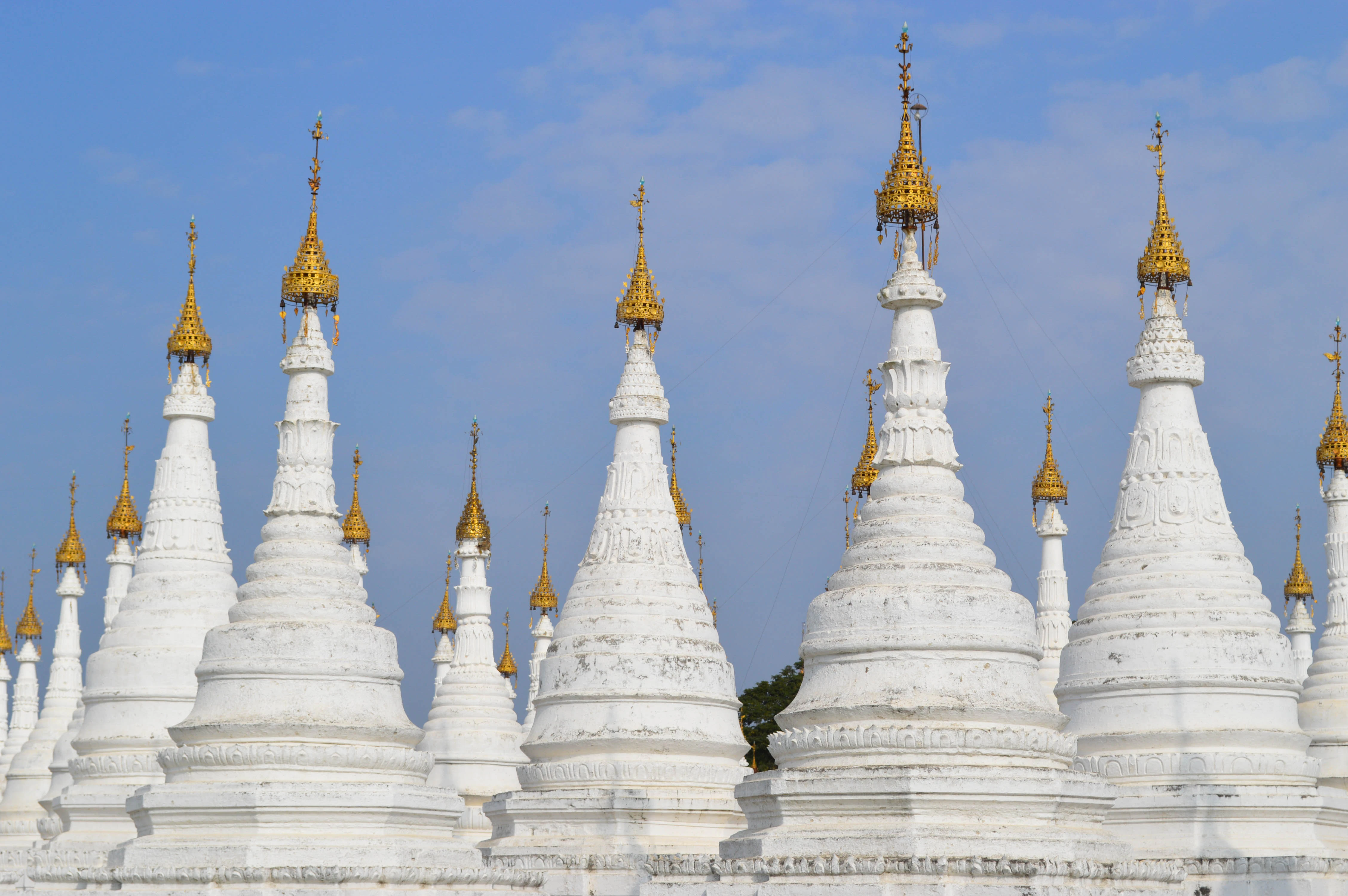 a row of white and gold spires against a blue sky