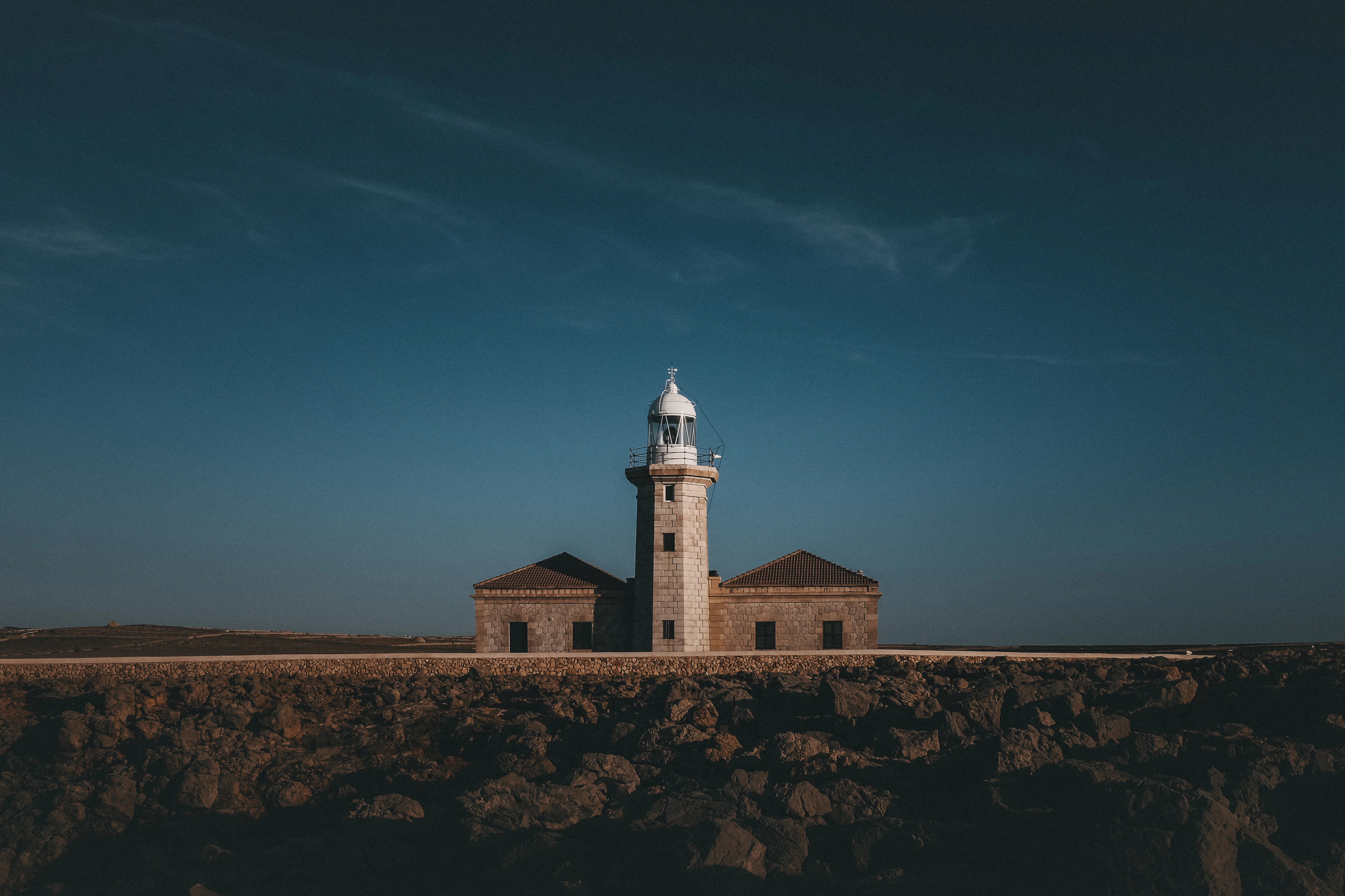 a lighthouse on top of a cliff under a blue sky