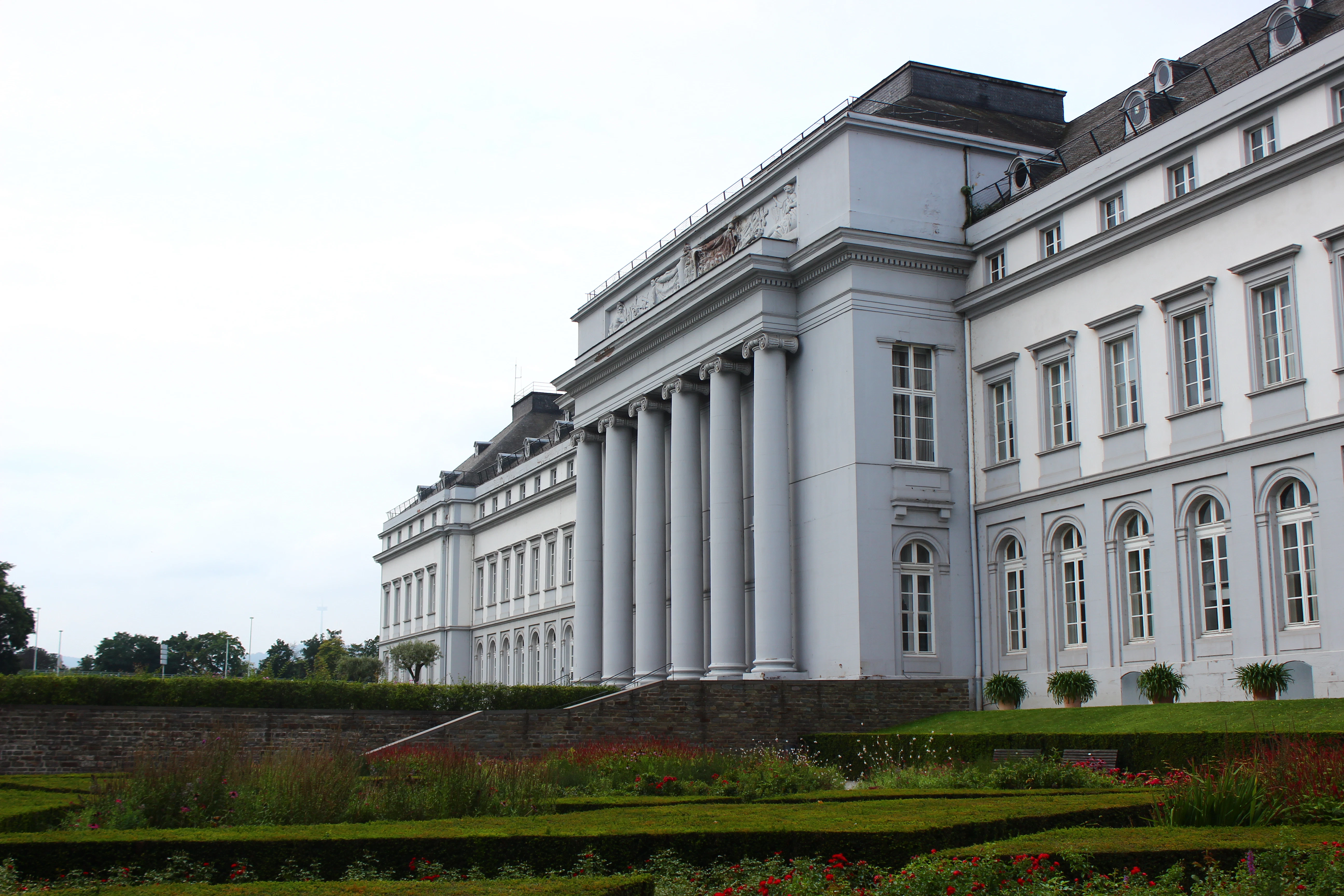 a large white building sitting next to a lush green park