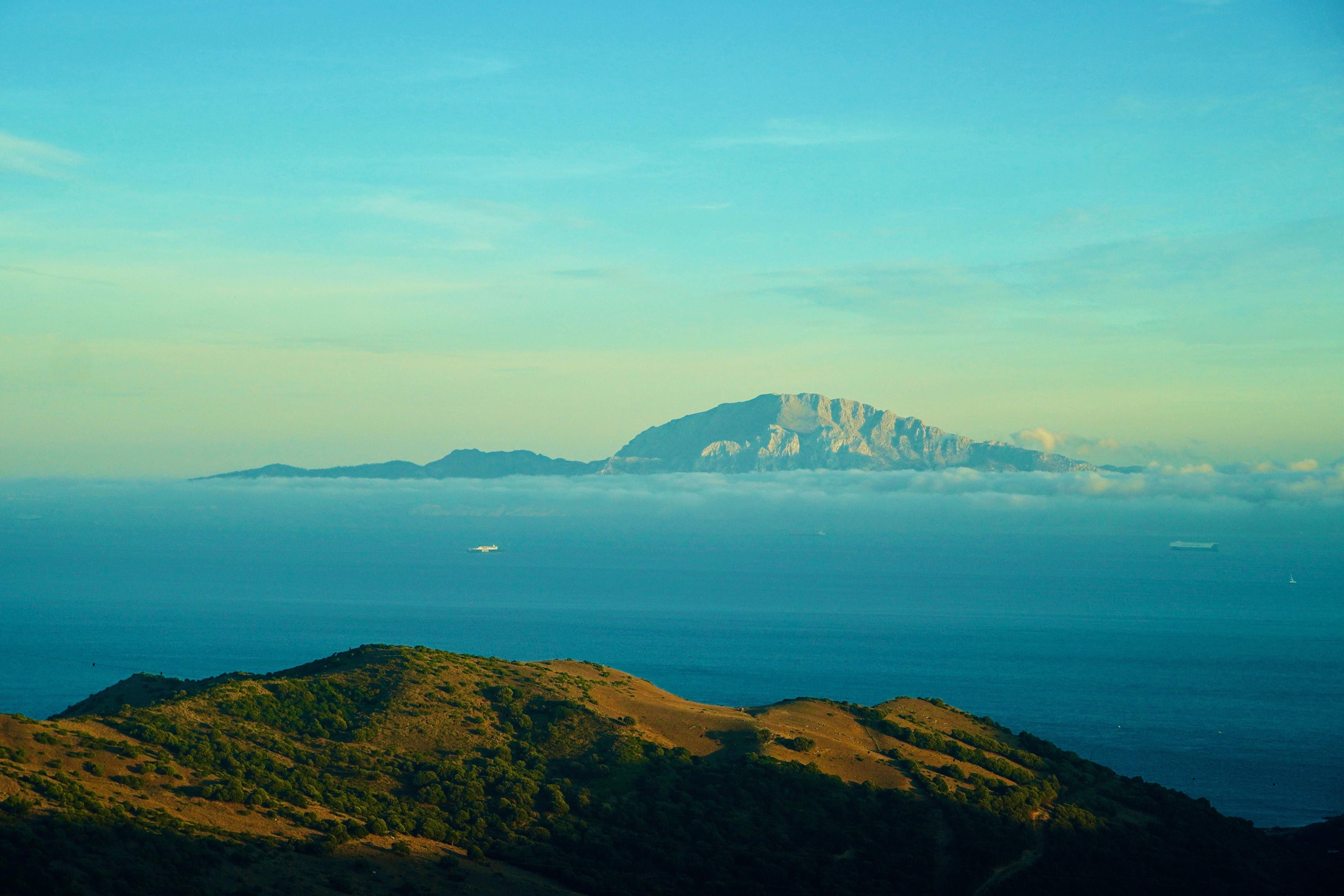 Distant mountain range across the ocean under sky