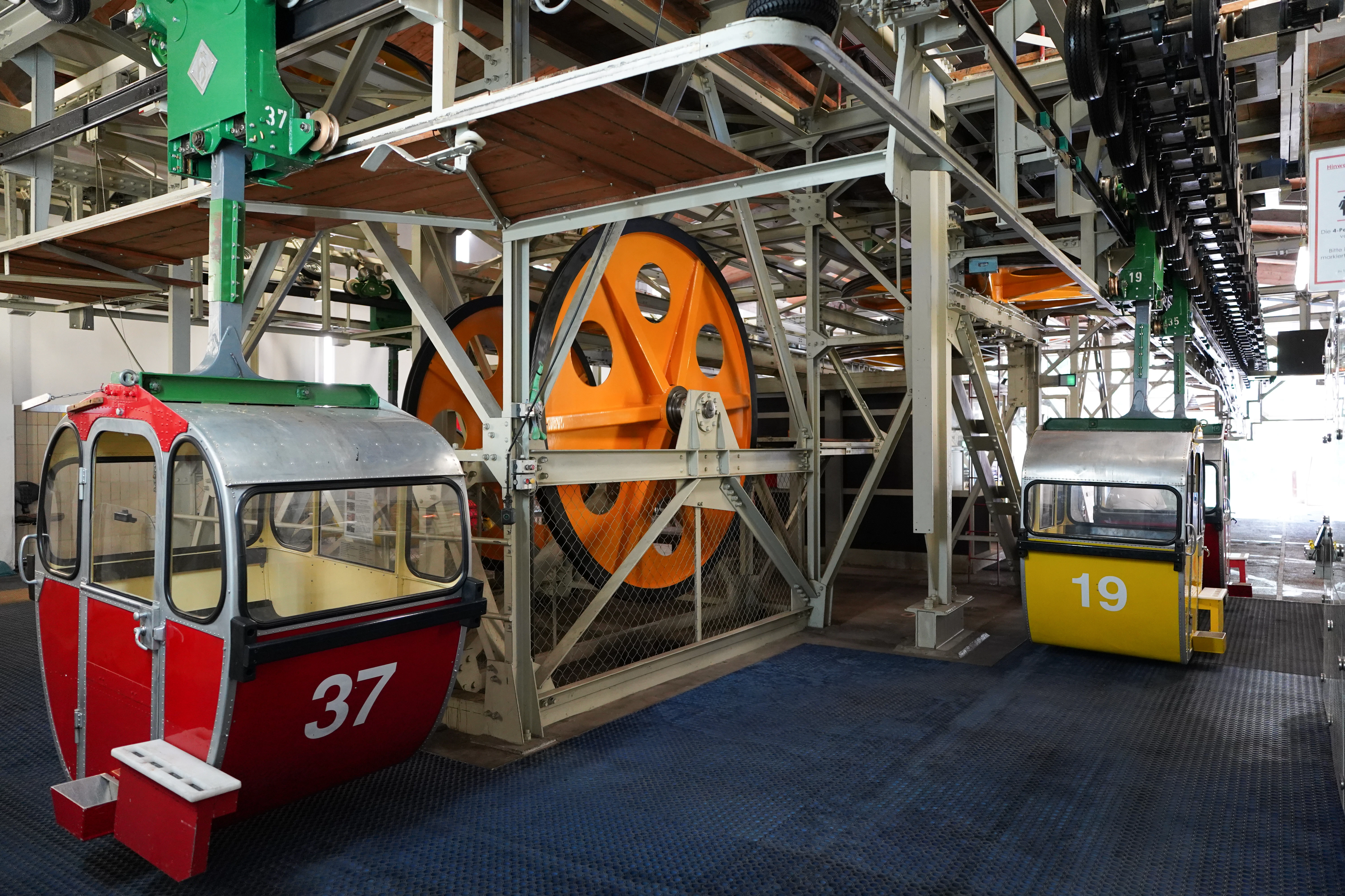 Two cable cars at a station with large wheels