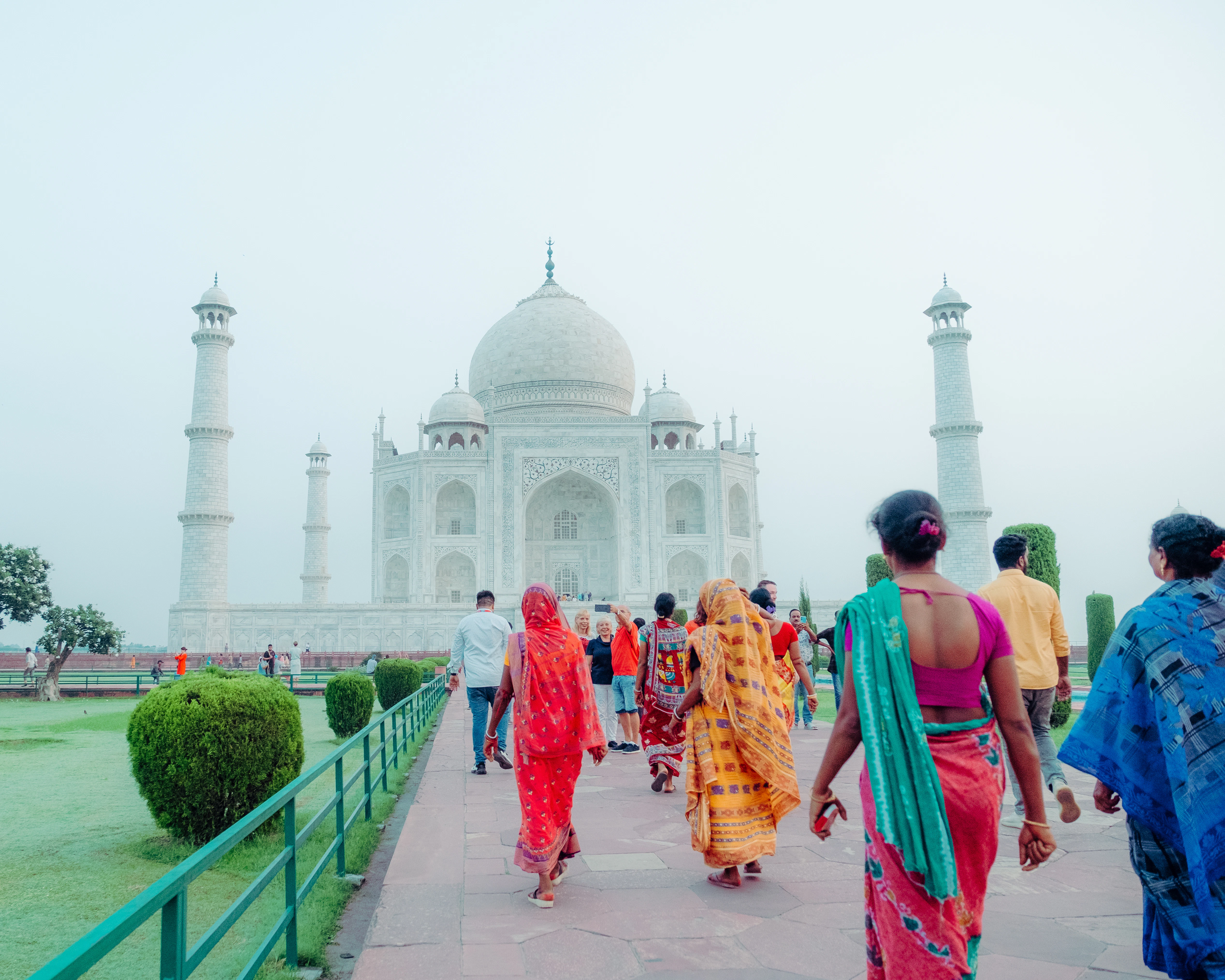 A group of people walking down a sidewalk in front of a white building