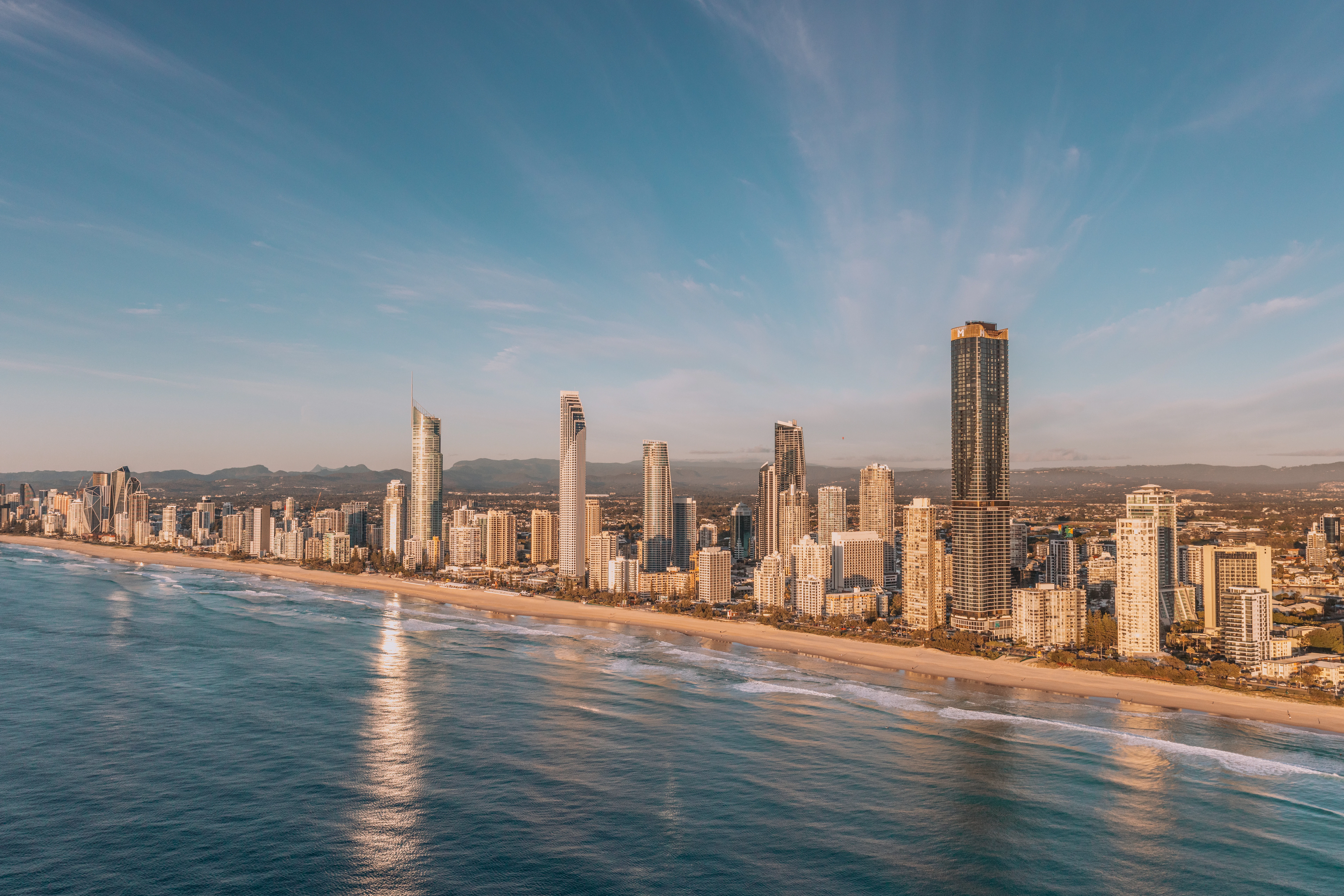 Modern city skyline along a sandy beach and ocean.