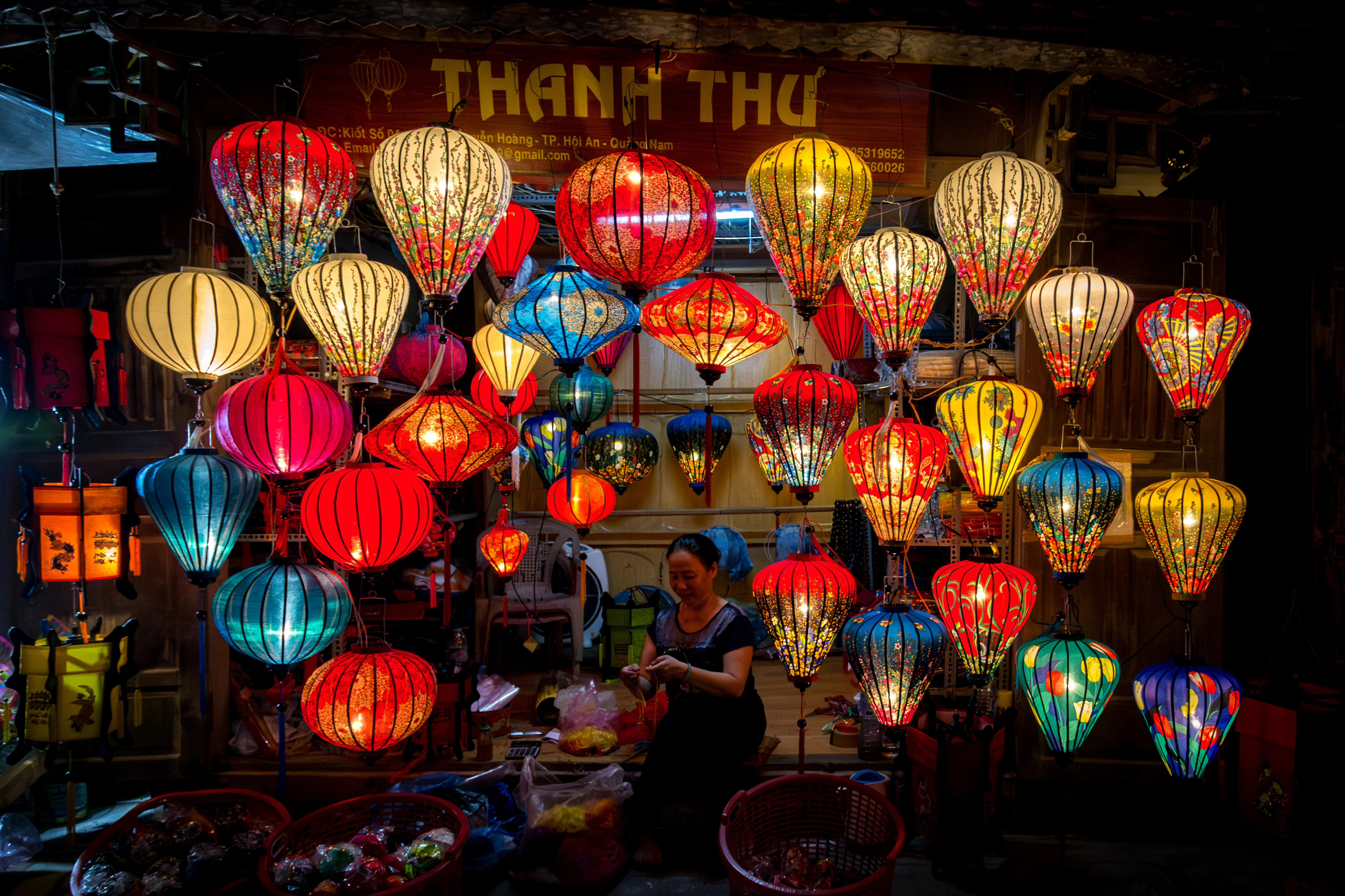 Colorful lanterns illuminate a night market with people browsing