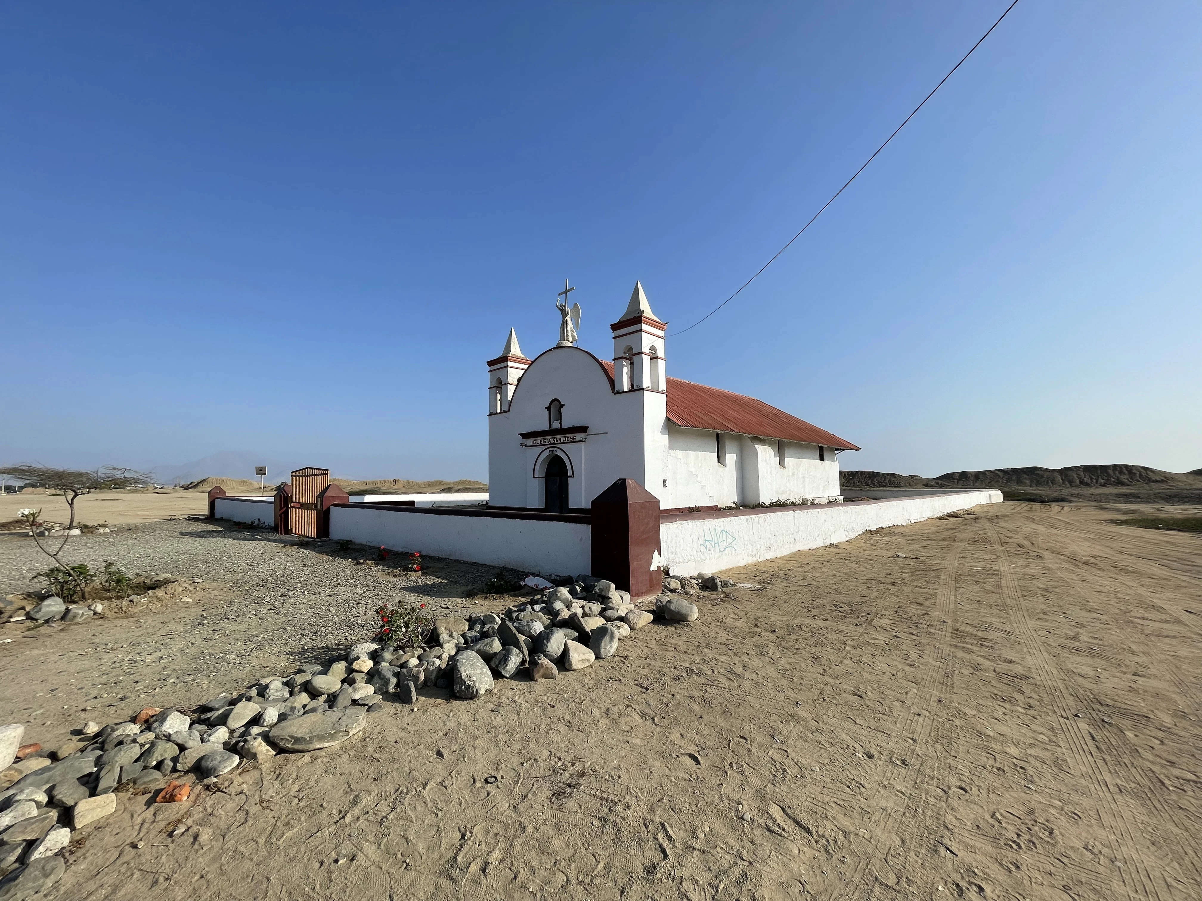A small white church sitting on top of a dirt field