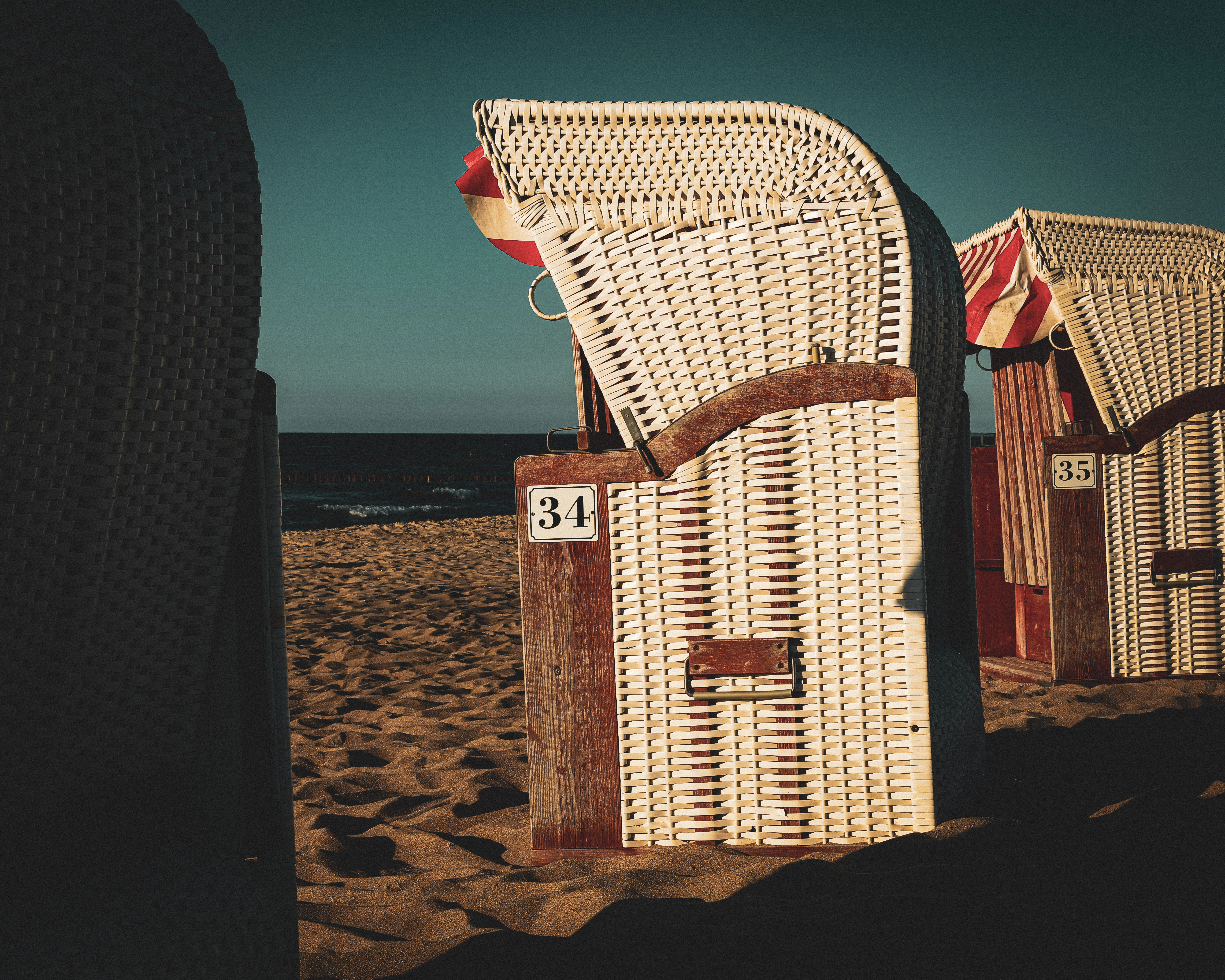 a couple of chairs sitting on top of a sandy beach